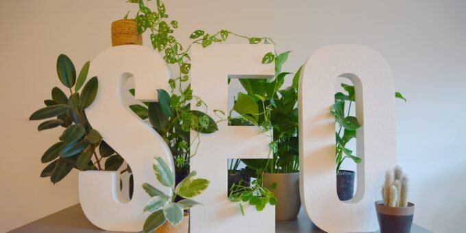 a white sign with plants and a potted plant next to it