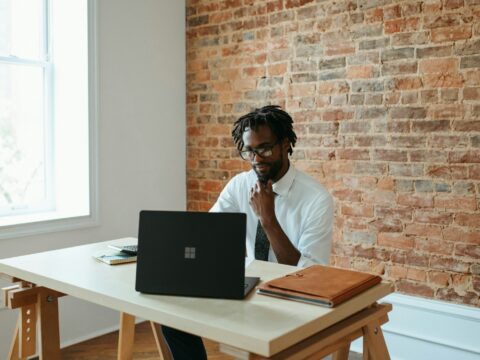 a man sitting at a table in front of a laptop