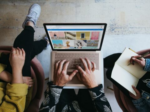 person using microsoft surface laptop on lap with two other people